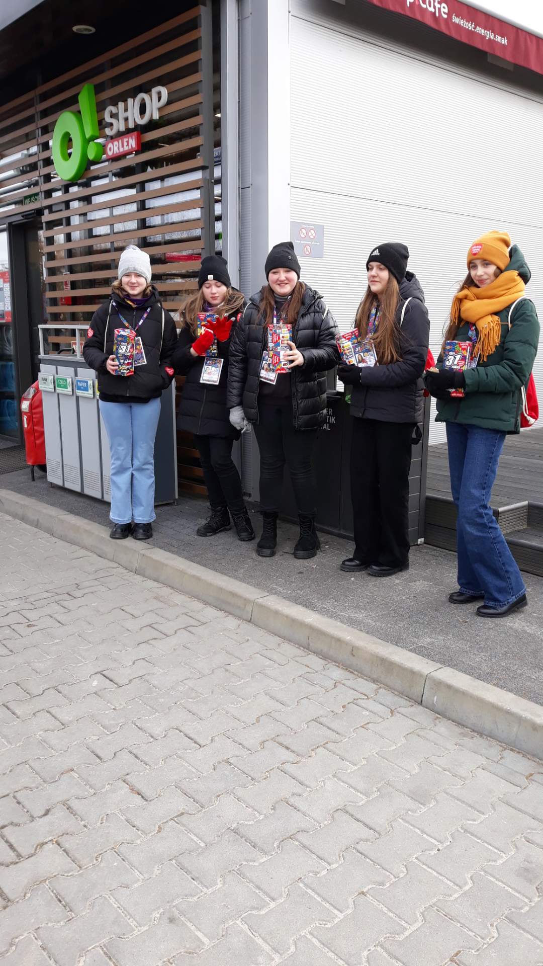 Uczennice jako wolontariusze 31. finału WOŚP przed budynkiem stacji paliw Orlen