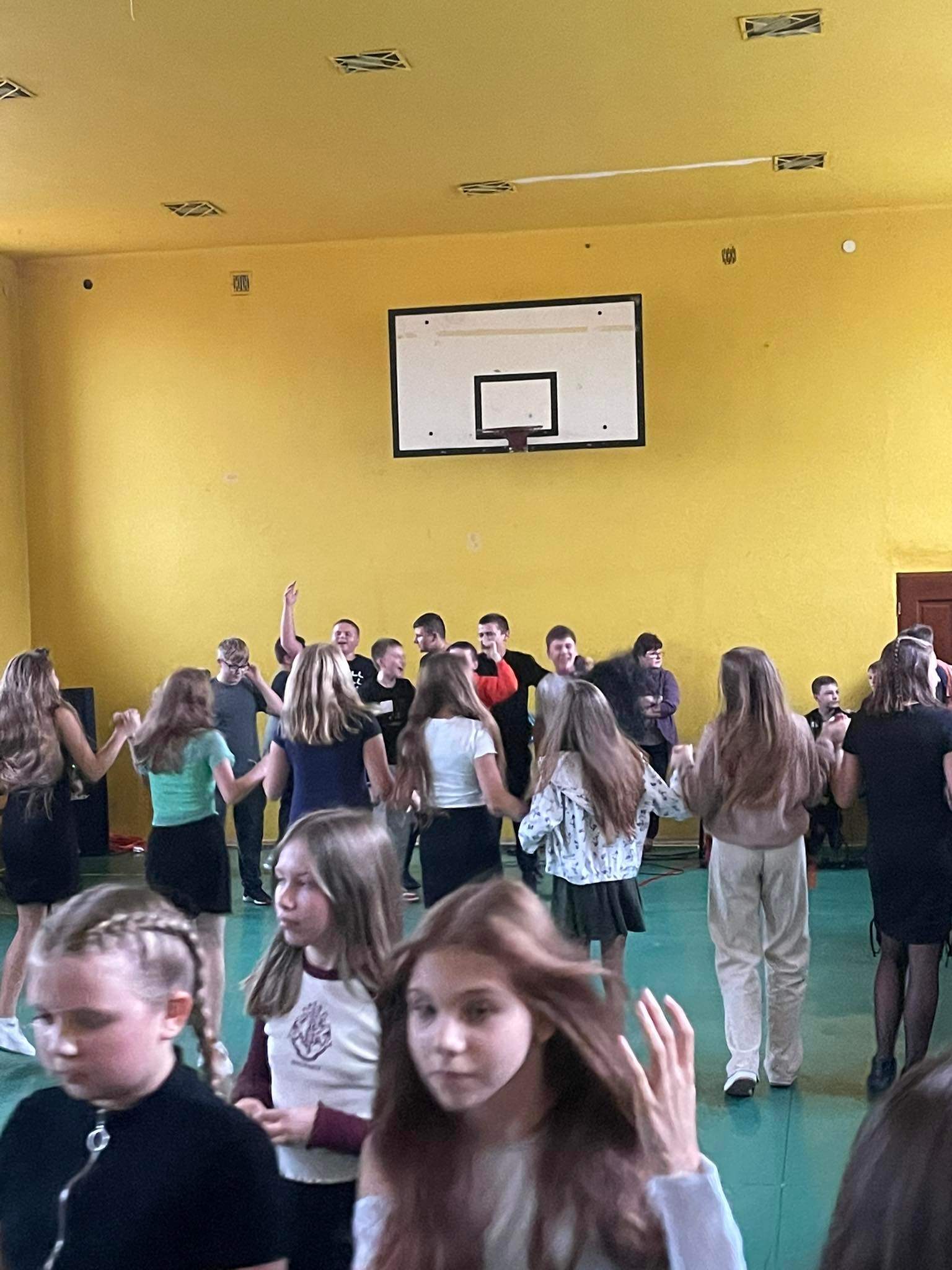 Uczniowie tańczący w sali gimnastycznej.